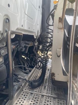 Coiled trailer cable routed behind the cab of a Mercedes-Benz Actros at the tractor-trailer connection